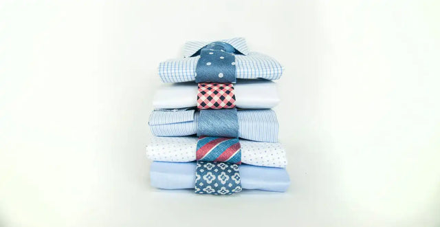 Montón de camisas de vestir bien dobladas con varios patrones y diseños.