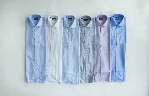 Seis camisas de vestir organizadas neatamente en diferentes tonos de azul, gris y rayas moradas.