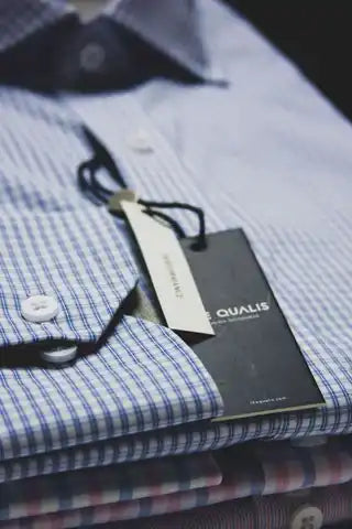 Camisa de vestir doblada con una etiqueta de precio negra adjunta.