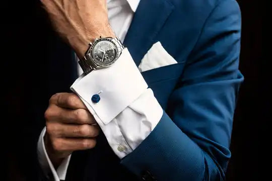 Reloj de muñeca elegante usado con un traje azul marino y una camisa blanca de vestir con gemelos.