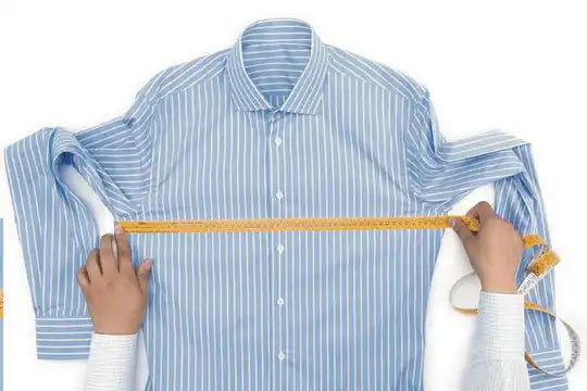 Camisa de vestir a rayas azul claro y blanca siendo medida con una cinta métrica amarilla.