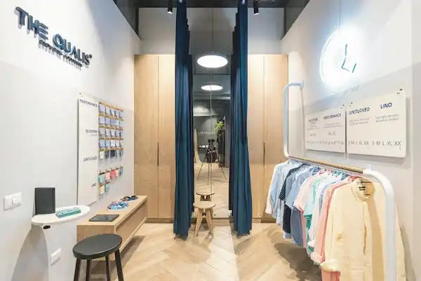 Tienda de ropa moderna con cortinas azul verdoso y prendas colgantes.
